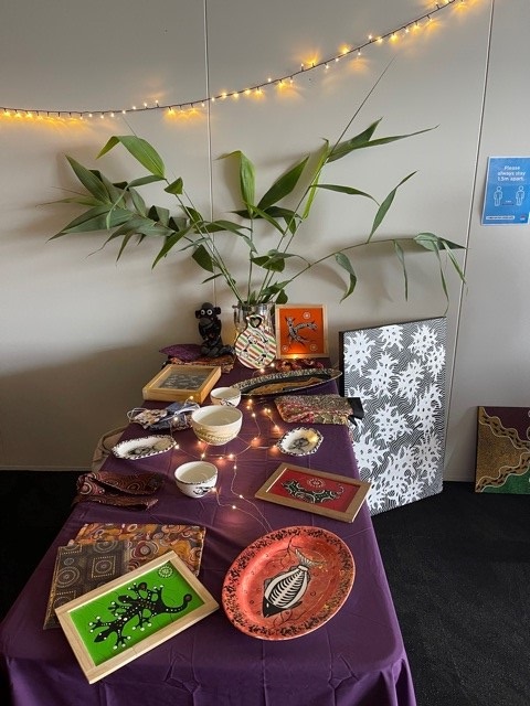 Fairy lights above a table holding Aboriginal paintings, cups and plates with Aboriginal designs