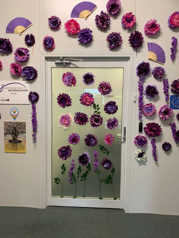 Newcastle WDVCAS door decorated for International Women's Day with purple paper flowers and fans