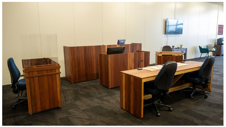 The mock courtroom at NWDVCAS, featuring built wooden furniture, screens and chairs that imitate the layout of a courtroom